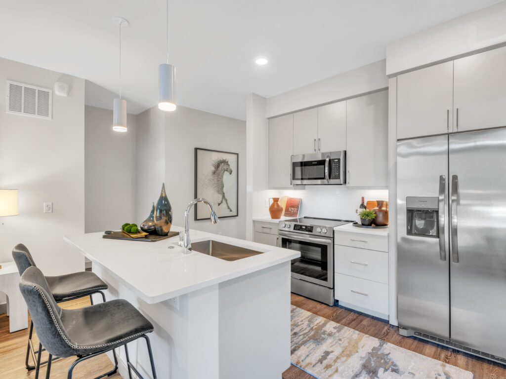 Modern kitchen with stainless steel appliances, white cabinetry, and a central island with bar stools.