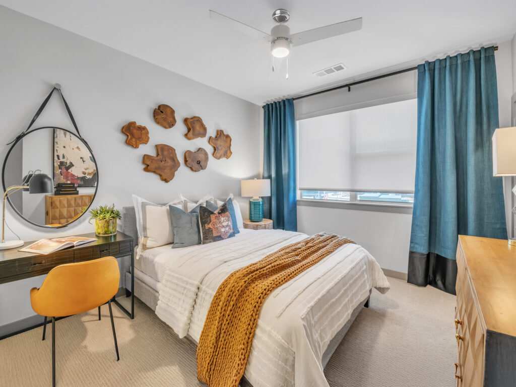 Bedroom with white bedding, wood accents, blue curtains, and wall art