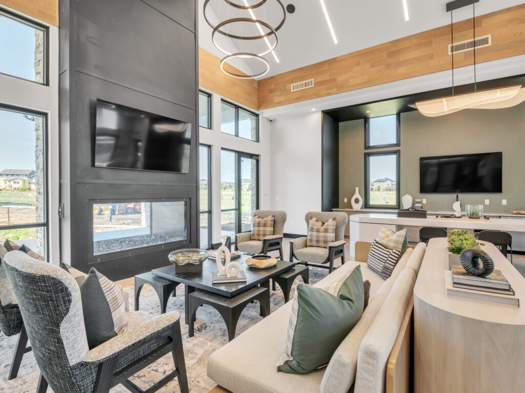 Modern living room with high ceiling, circular lights, multiple couches, and mounted TVs